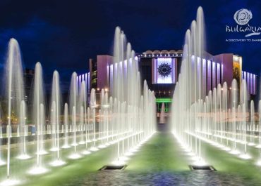 A grand fountain with water jets in front of a majestic building.