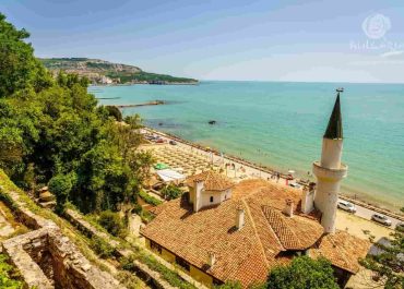 A serene beach with a picturesque church perched on a hillside, creating a beautiful coastal landscape.